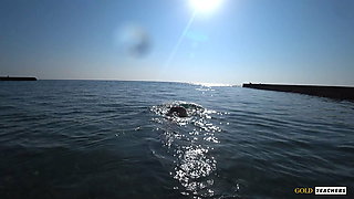 Nude model swims on a public beach in Russia.