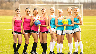 A group of teens play a game of naked soccer while outdoors
